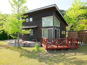a wooden house with a large deck in front of it at Mt Ichibata Cottage in Izumo