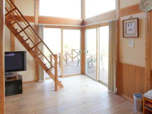 a living room with sliding glass doors and a staircase at Mt Ichibata Cottage in Izumo
