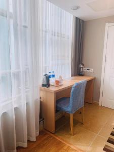 a desk with a blue chair next to a window at Home Inn Mianyang People'S Park in Mianyang