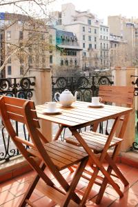 une table et une chaise en bois assises sur un balcon dans l'établissement Casa Valeta, à Barcelone