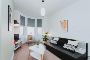 a living room with a black couch and a table at BRAND NEW TOWNHOUSE IN RUGBY in Rugby