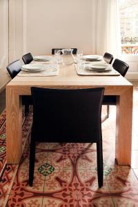 a dining room table with a black chair and a table with plates at Casa Valeta in Barcelona