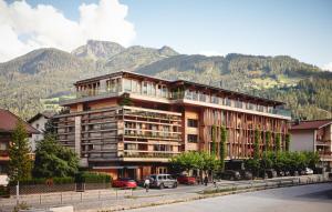 a large building with mountains in the background at Small Luxury Hotel of the World - DasPosthotel in Zell am Ziller