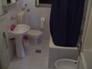 e bagno con lavandino, servizi igienici e tenda per la doccia. di Guest House Villa Jadera a Zara (Zadar)