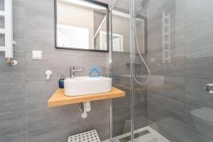 uma casa de banho com um lavatório e um chuveiro em Aura Sopot Studio Apartments em Sopot
