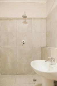 ein weißes Bad mit einem Waschbecken und einer Dusche in der Unterkunft The Square Holiday Apartments in Kapstadt