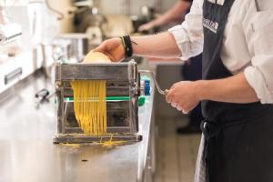 a person in a kitchen with a container of spaghetti at MONDI Hotel am Grundlsee in Grundlsee
