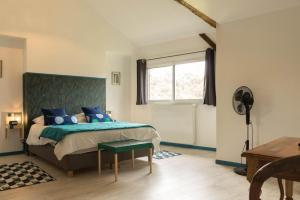 Un dormitorio con una cama con almohadas azules y una ventana en Maison entre Campagne et Foret, en Aspret-Sarrat