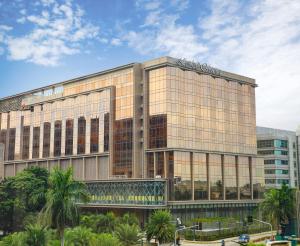 Hotel Okura Manila - Staycation Approved في مانيلا: مبنى مكتب كبير أمامه أشجار نخيل