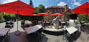 a patio with a fountain and tables and red umbrellas at Hotel Le Monte Cristo in Mons