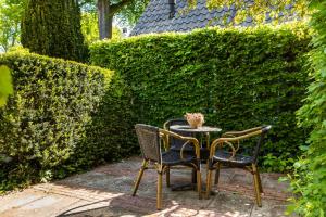 two chairs and a table in front of a hedge at Hotelroom Villa 1913 in Bergen