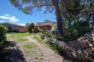 uma casa com uma parede de pedra e uma árvore em Villa Bados 6 - Klodge em Olbia