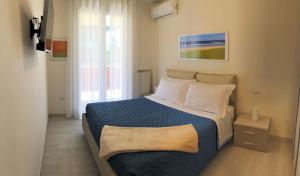 ein Schlafzimmer mit einem Bett mit einer blauen Decke und weißen Kissen in der Unterkunft Residenza VerdeMare in Misano Adriatico