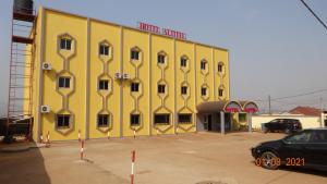 a yellow building with a car parked in front of it at Hôtel Altitel in Bafoussam