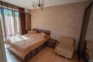 a bedroom with a bed and a chair and a window at Park Residence Forest View in Bakuriani +15 photos