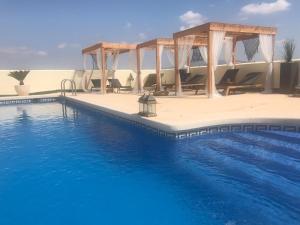 a pool with chairs and a gazebo at Rancho de Sueños in La Zarza
