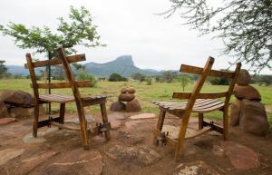 two wooden chairs and a table on a rock at Legend Golf and Safari Resort in Sterkrivier
