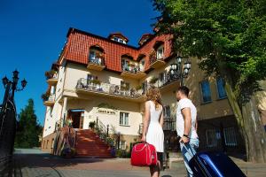 un homme et une femme debout devant un bâtiment dans l'établissement Hotel Adam & Spa, à Kudowa-Zdrój