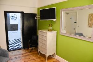 a green room with a dresser and a mirror at The Bank Hotel & Bistro in Hastings