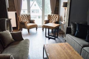 ein Wohnzimmer mit Sofas, Stühlen und einem Tisch in der Unterkunft StrandBerg's Ursprung: Spa & Kitchen in Braunlage