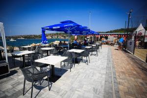 a row of tables and chairs with blue umbrellas at Apartment Bonaca in Portorož