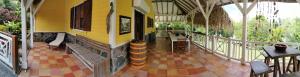 - un bâtiment jaune avec une terrasse dotée de tables et de chaises dans l'établissement Villa CACAO, à Rivière-Salée