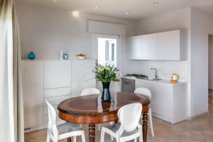een keuken met een houten tafel en witte stoelen bij Viareggio Suite - Sea view apartment in Viareggio