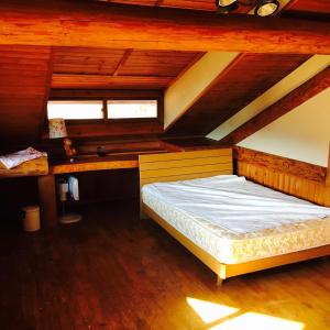 a bed in a room with a wooden ceiling at NaGano-log house in Chino