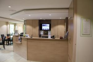 an office with a reception counter with a tv in a room at Logis Lhôtel Restaurant Antony Verrières Le Buisson in Verrières-le-Buisson