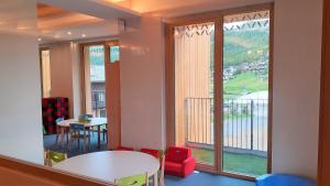 a room with a table and chairs and a large window at Livì Family Hotel in Livigno