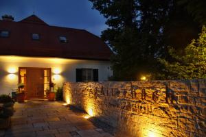 ein Haus mit einer Steinmauer und einem Zaun mit Licht in der Unterkunft Hotel Aiterbach am Chiemsee in Rimsting