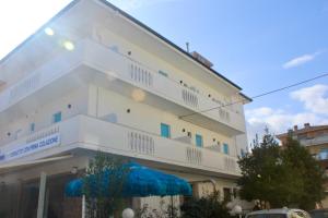 a white building with a blue umbrella in front of it at Hotel Tuo Mare in Silvi Marina