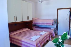 two beds in a room with pink and purple sheets at Hotel Tuo Mare in Silvi Marina