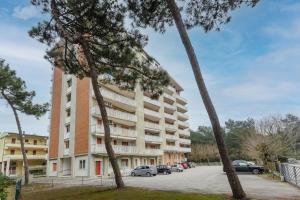 an apartment building with cars parked in a parking lot at Lido di Spina vista mare pineta - A Casa di Alessandra in Lido di Spina