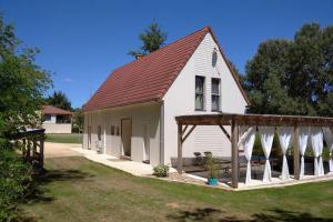 a white house with a gazebo and white surfboards at Les Maisons du Marais in Groléjac