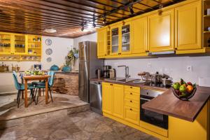 cocina con armarios amarillos y mesa en Villa Evridiki by Pelion Esties, en Agios Georgios Nilias