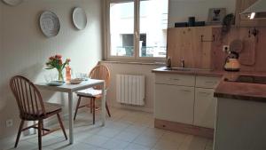 een keuken met een tafel en stoelen en een tafel en een raam bij T2 G dans maison en centre ville avec jardin ideal couple curistes in Balaruc-les-Bains