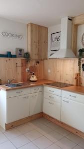 een keuken met witte kasten en een wastafel bij T2 G dans maison en centre ville avec jardin ideal couple curistes in Balaruc-les-Bains