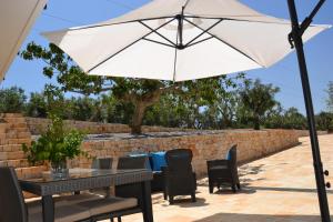 einen Tisch und Stühle mit Sonnenschirm auf einer Terrasse in der Unterkunft Il Crepuscolo Apartment - Villaggio di Mary in Locorotondo