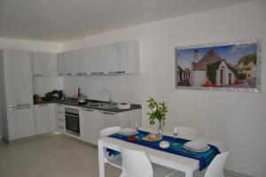 una cucina con tavolo, sedie e piano di lavoro di Il Crepuscolo Apartment - Villaggio di Mary a Locorotondo