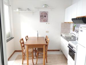 Il comprend une petite cuisine avec une table et des chaises en bois. dans l'établissement Appartamenti Magnolia, à Positano