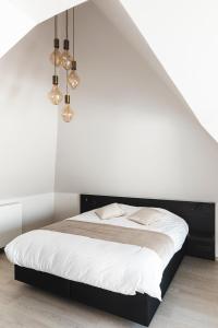 - une chambre dotée d'un lit avec des murs blancs et des lumières dans l'établissement Salons Denotter, à Zedelgem