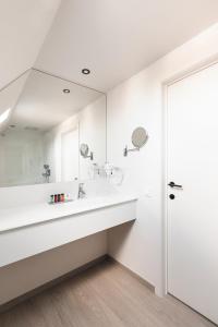 La salle de bains blanche est pourvue d'un lavabo et d'un miroir. dans l'établissement Salons Denotter, à Zedelgem