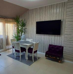 a dining room with a table and chairs and a tv at Hétvezér Penthouse Apartments in Szeged