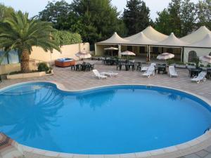 a large blue pool with chairs and tables and umbrellas at Hotel Califfo in Quartu SantʼElena