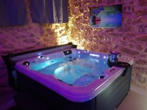 CampagnanにあるGîte Love Dreams Jacuzzi privatifの紫色の照明が備わる客室内のジャクジーバスタブ