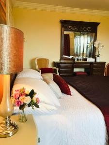Un dormitorio con una cama con una lámpara y flores. en Hillcrest farmhouse Bed & Breakfast en Boyhollagh