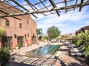 an outdoor swimming pool with chairs and a building at Dar Tafantant in Marrakech