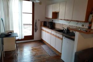 eine Küche mit weißen Schränken und einem Holzboden in der Unterkunft Meublé tourisme classé 1 étoile - coeur de ville quartier cathédrale in Tours