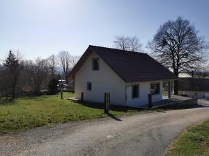 uma casa branca com um telhado preto numa estrada em La Maison du Colombier em Le Fied